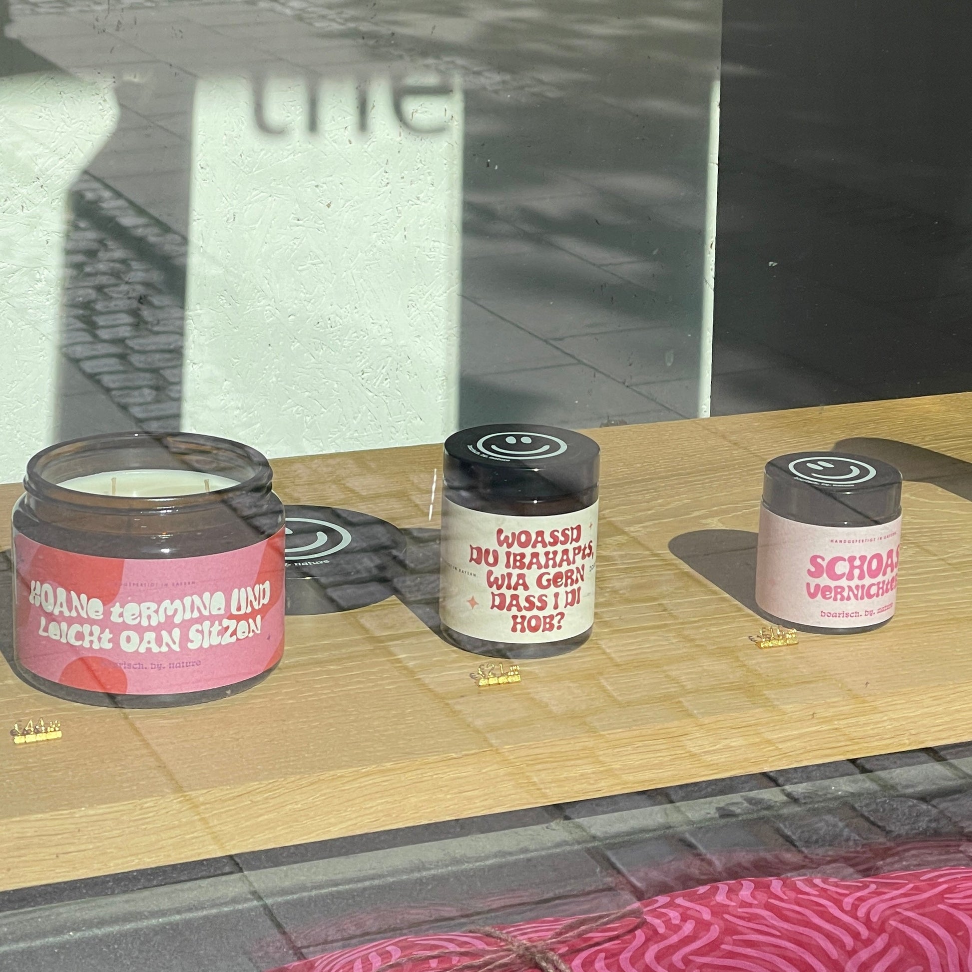 Drei Kerzen sind im Schaufenster ausgestellt. jede mit einem anderen Spruch