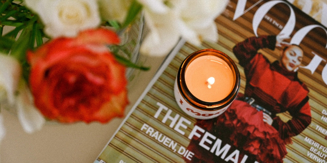Eine brennende Kerze von oben auf einem Tisch  mit Rosen und einem Magazin