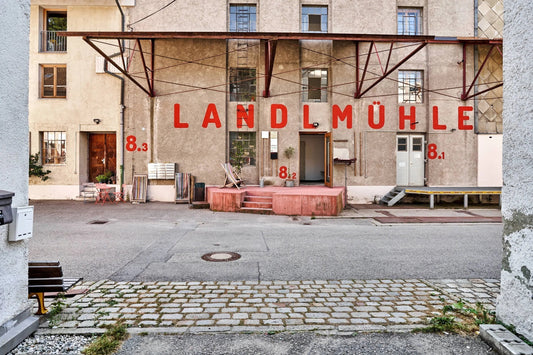 Ein Hinterhof und Lagerhaus mit modernen Gartenmöbeln und der Aufschrift LANDLMÜHLE auf der Wand