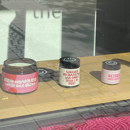 Drei Kerzen sind im Schaufenster ausgestellt. jede mit einem anderen Spruch